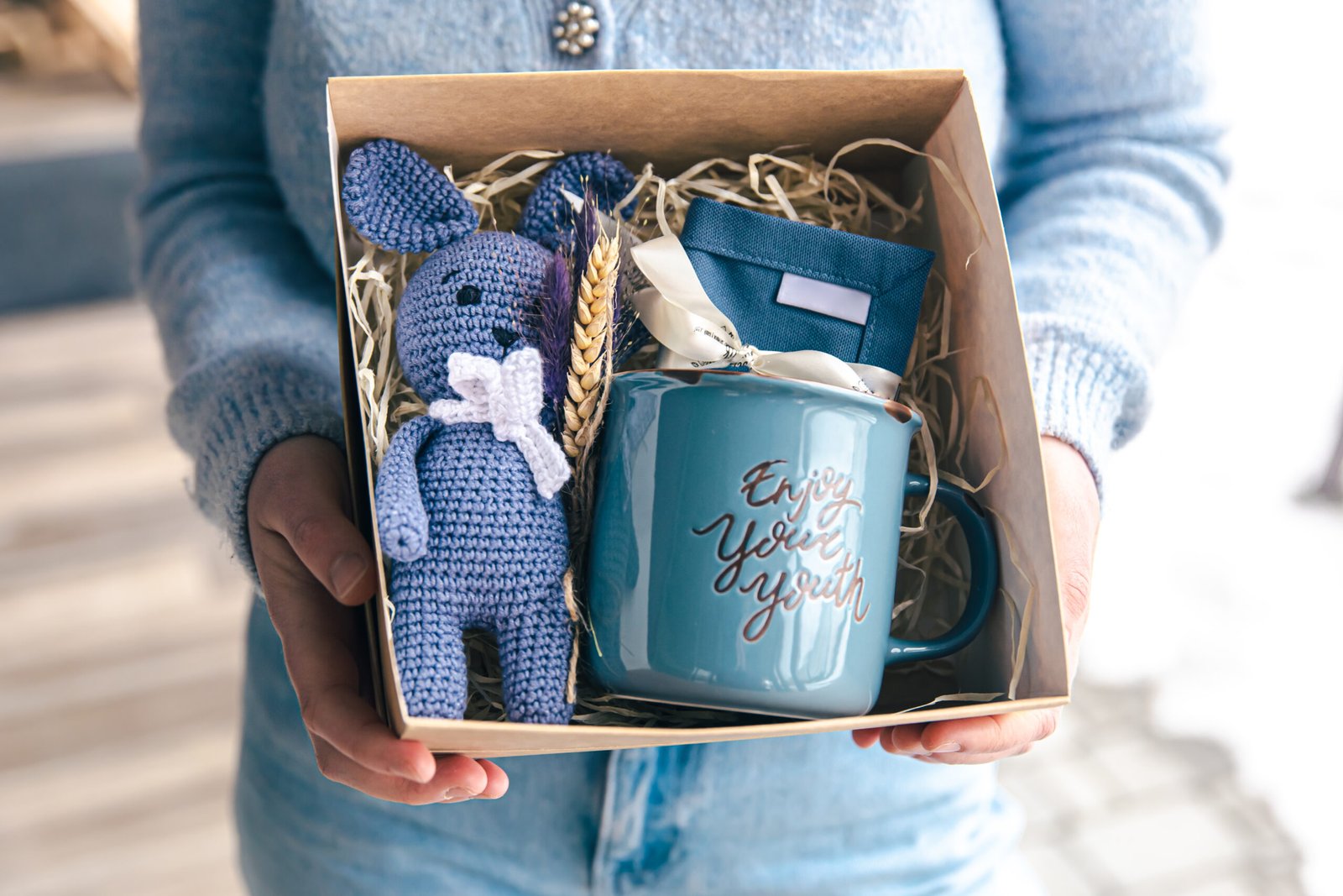 A blue cup with an inscription, a soft toy with a gift box for the holiday, a gift idea.